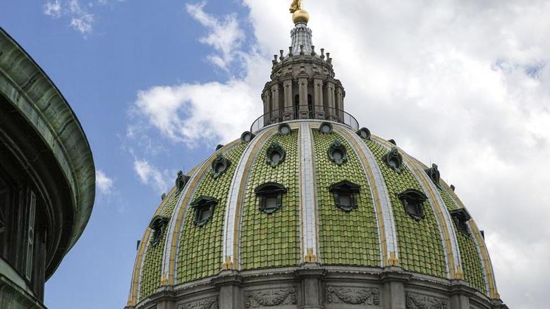 宾夕法尼亚州国会大厦的绿色和金色外墙映衬着蓝天白云.